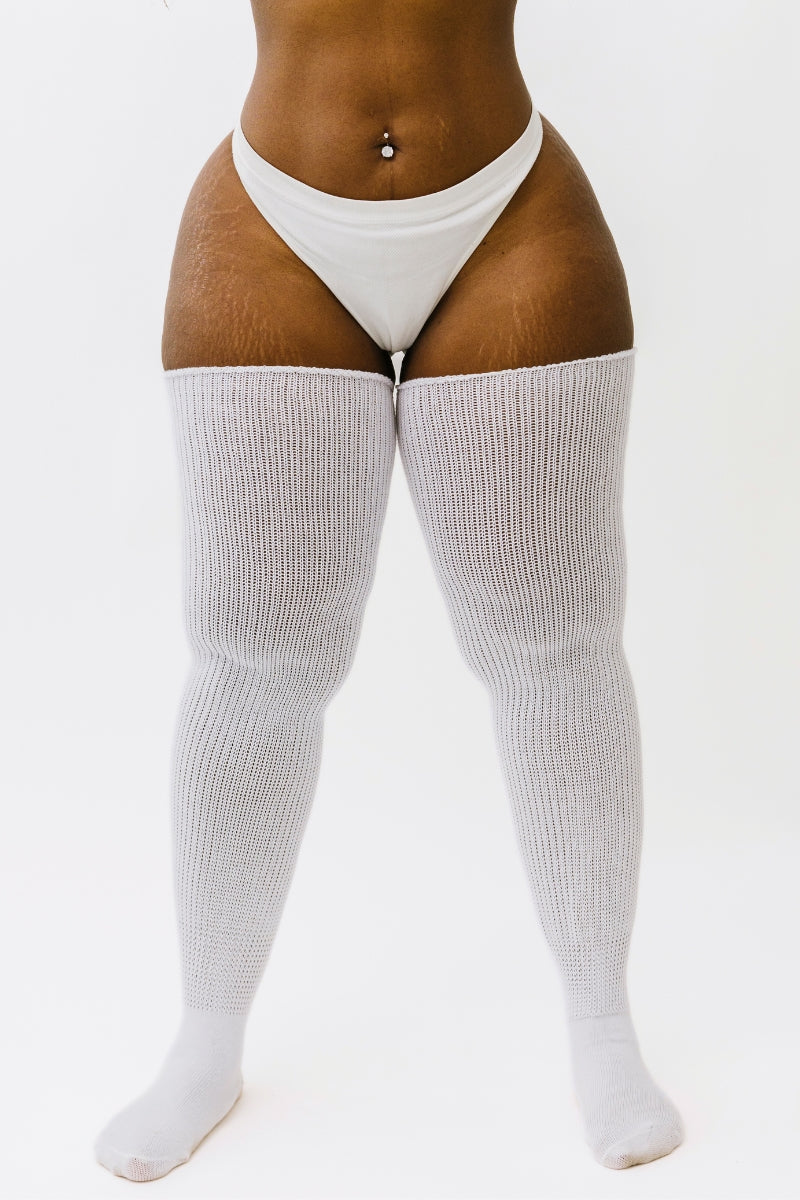 A pair of milky white thigh-high socks, displayed on a model. The socks are designed to fit over the upper legs and have a ribbed texture.