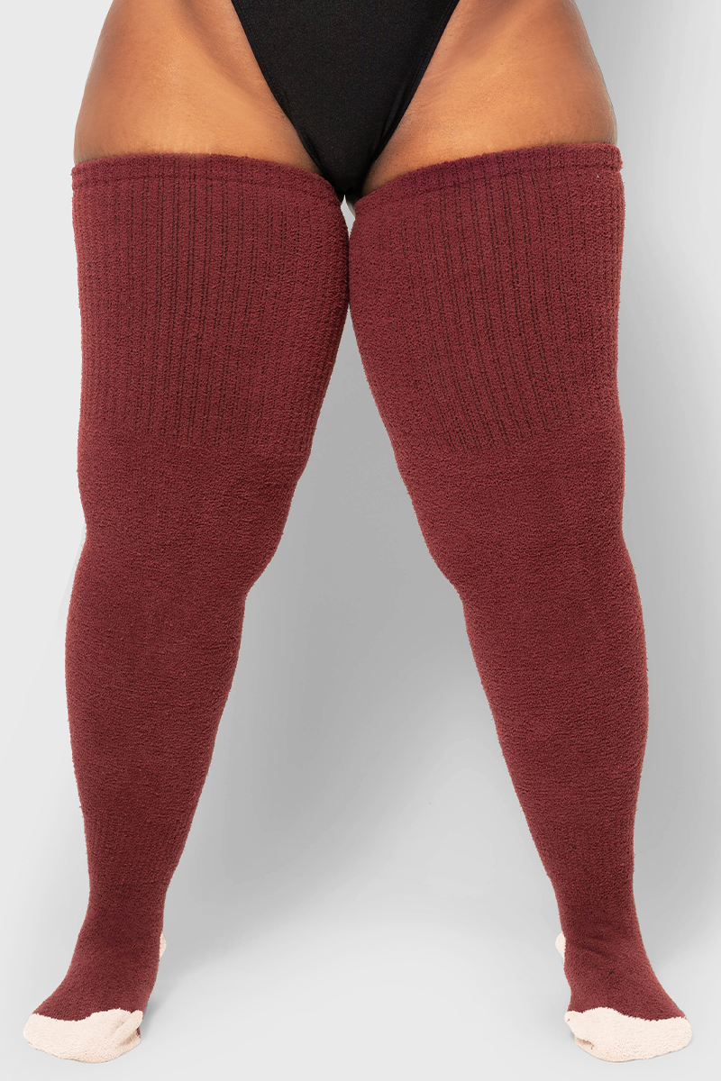 A pair of garnet red cozy bouclé-inspired fuzzy socks, showing the texture and length up to the thigh.