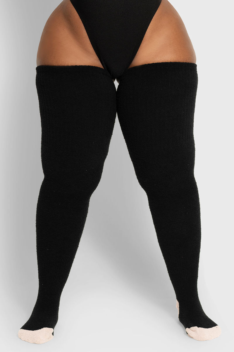 A pair of long black fuzzy socks designed to fit up to the thigh, made of brushed acrylic fabric.