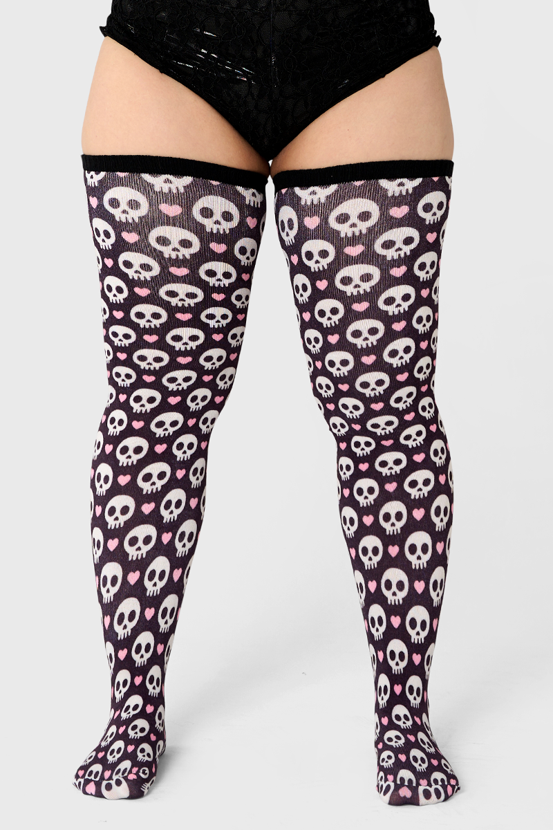 Thigh-high stockings with skull and heart pattern on a white background